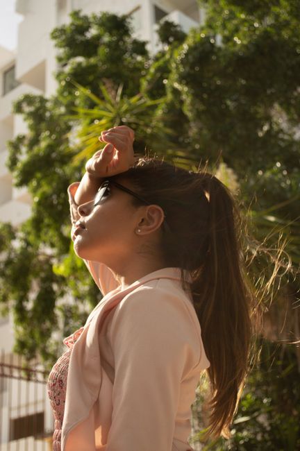 A stylish woman in sunglasses poses outdoors, enjoying the sunlight and summer vibes.