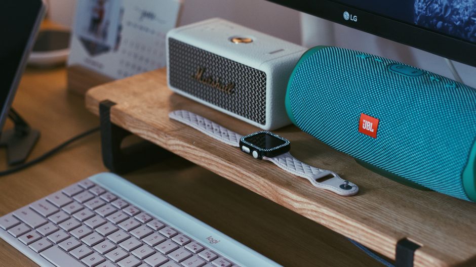 Best Smart Speaker Comparison: Alexa vs Google in 2025 A close-up of a modern workspace featuring Bluetooth speakers, a smartwatch, and a keyboard.