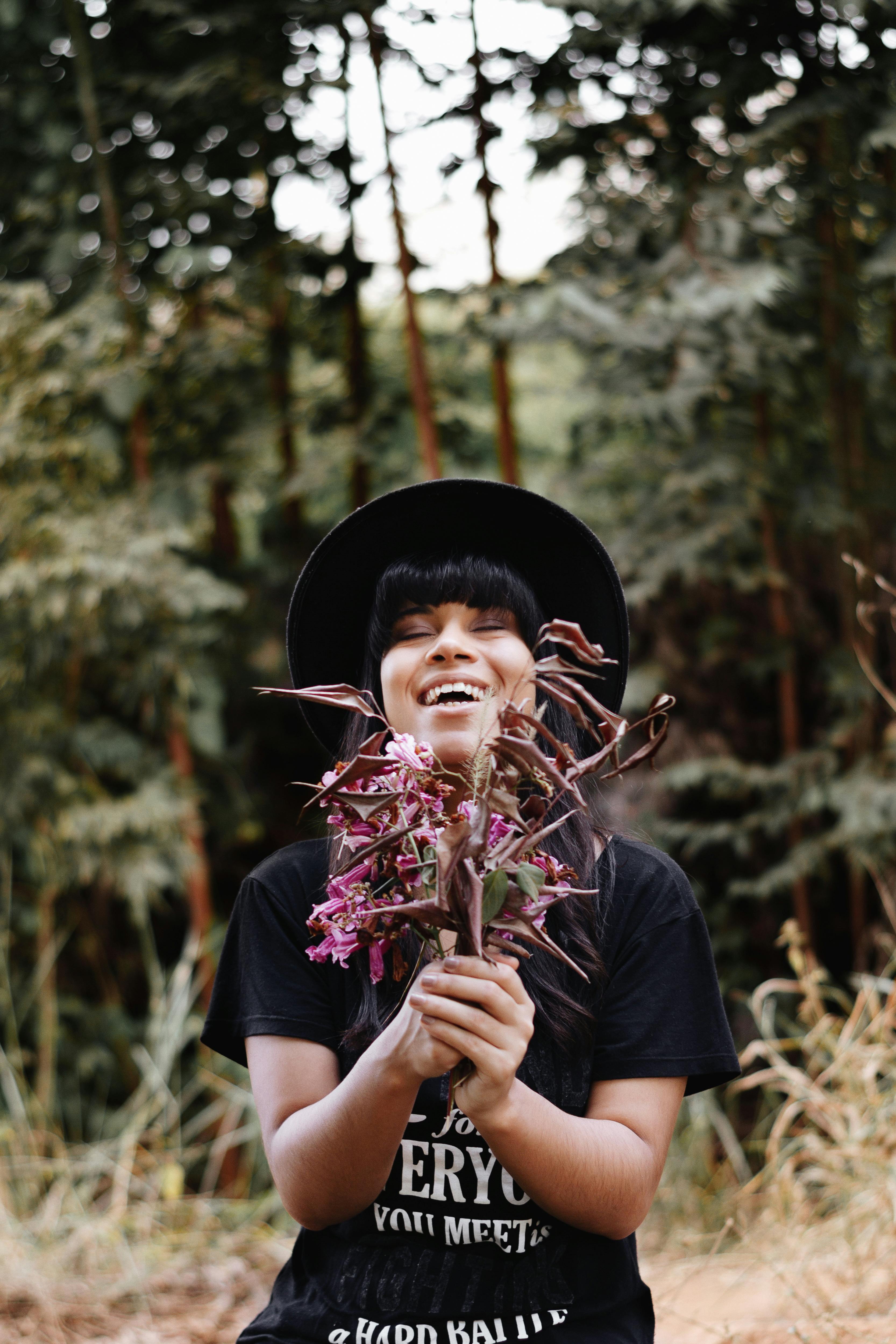 smiling woman with bunch of pink roses standing in woods