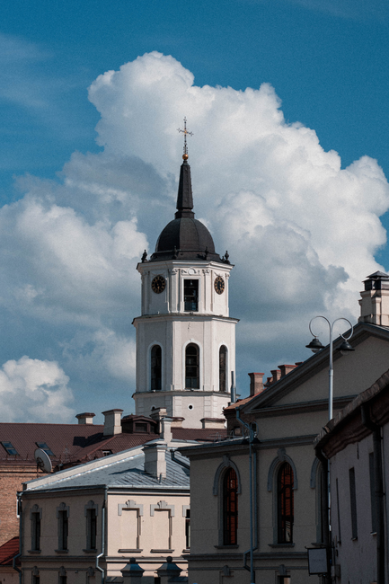 Neoclassical architecture of St. Stanislaus Cathedral bell tower against a cloudy sky in Vilnius, Lithuania.
