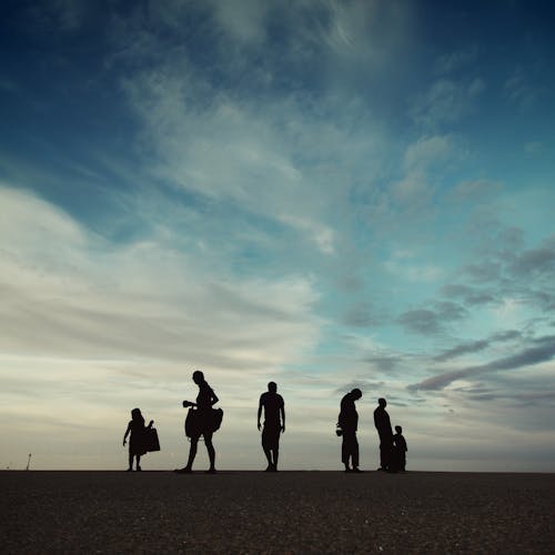 Фотография силуэта шести человек на песчаном поле