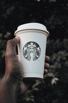 Close-up of a hand holding a coffee cup outdoors, perfect for lifestyle and beverage themes.