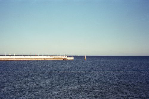 Free Calm ocean scene with a pier extending into the blue water under a clear sky. Stock Photo