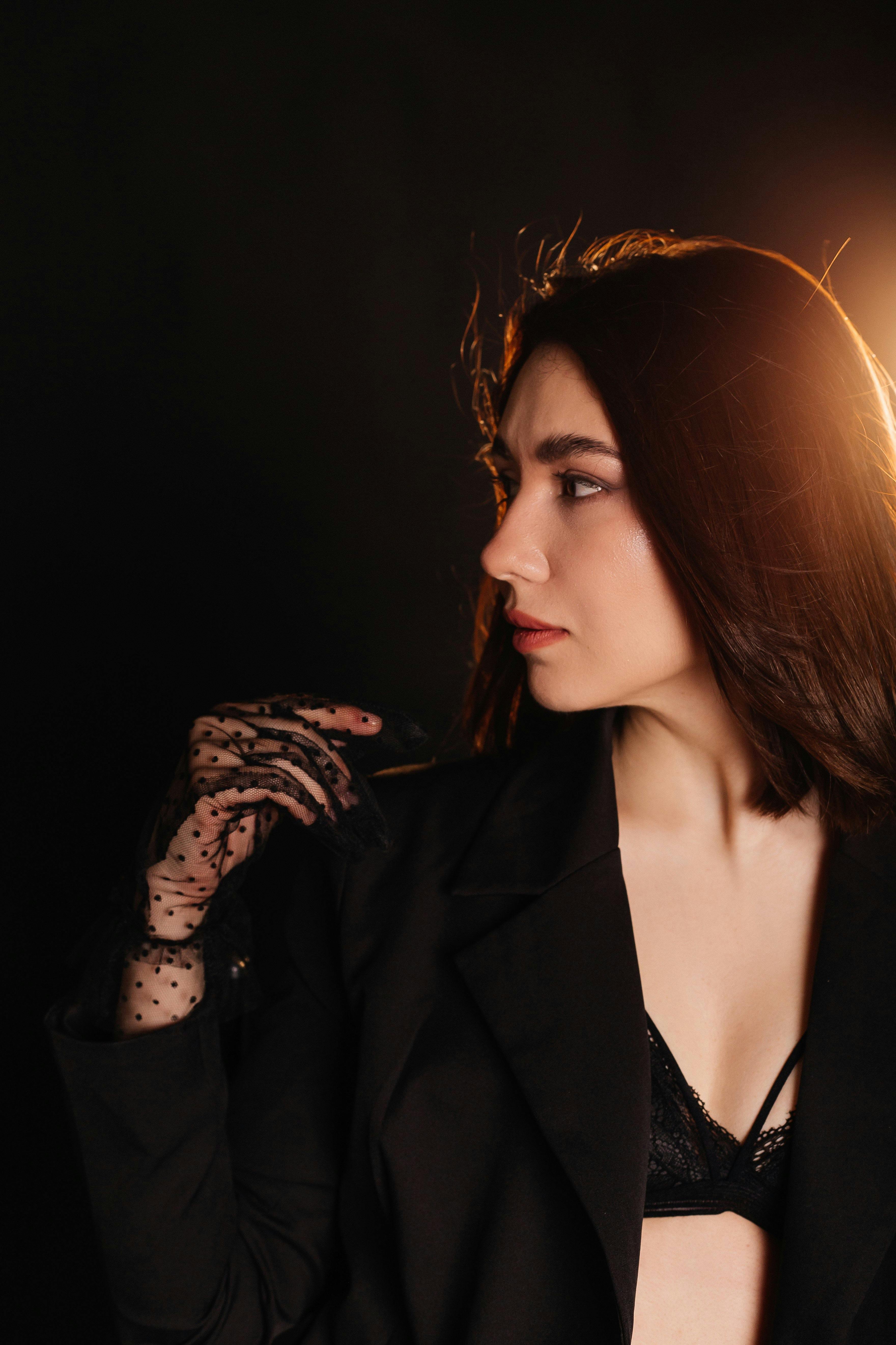 Portrait of a woman wearing a black blazer and lace glove, captured in dramatic lighting.