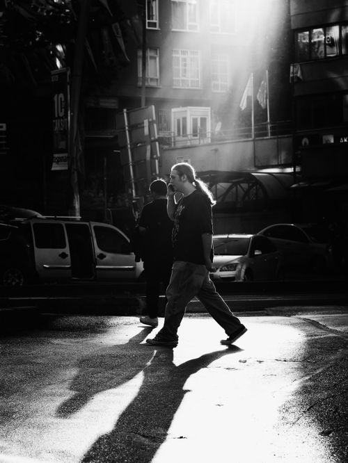 Free Dramatic street scene in Ankara capturing people crossing with striking light and shadows. Stock Photo