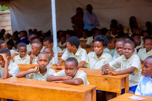 A group of African schoolchildren engaged in learning at an outdoor class setting.