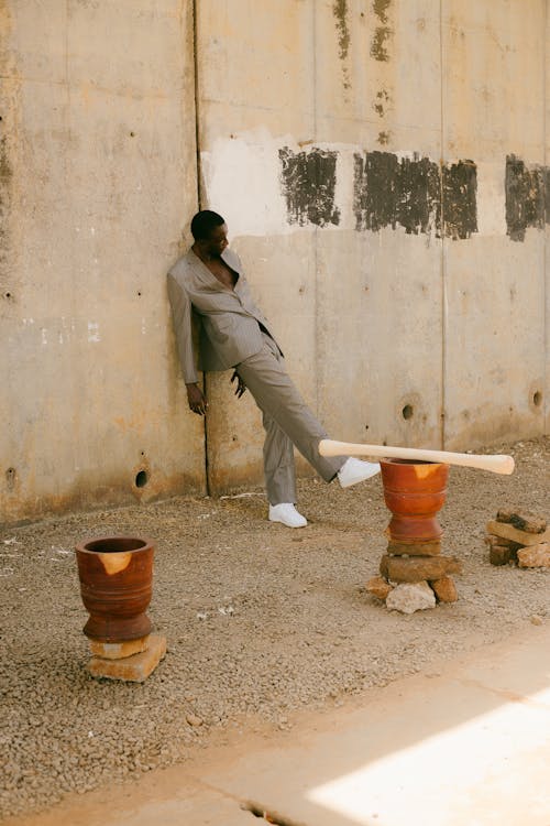 A man in a suit leaning against a wall with pots