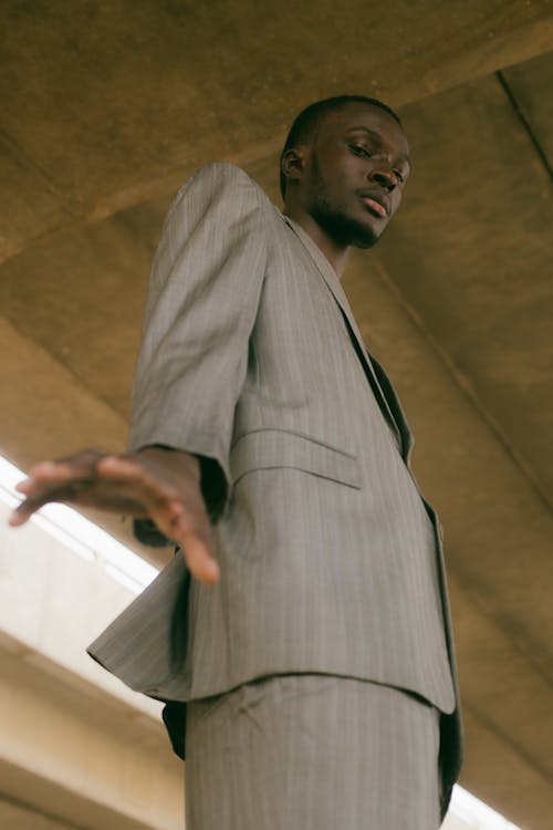 A man in a suit standing under a bridge