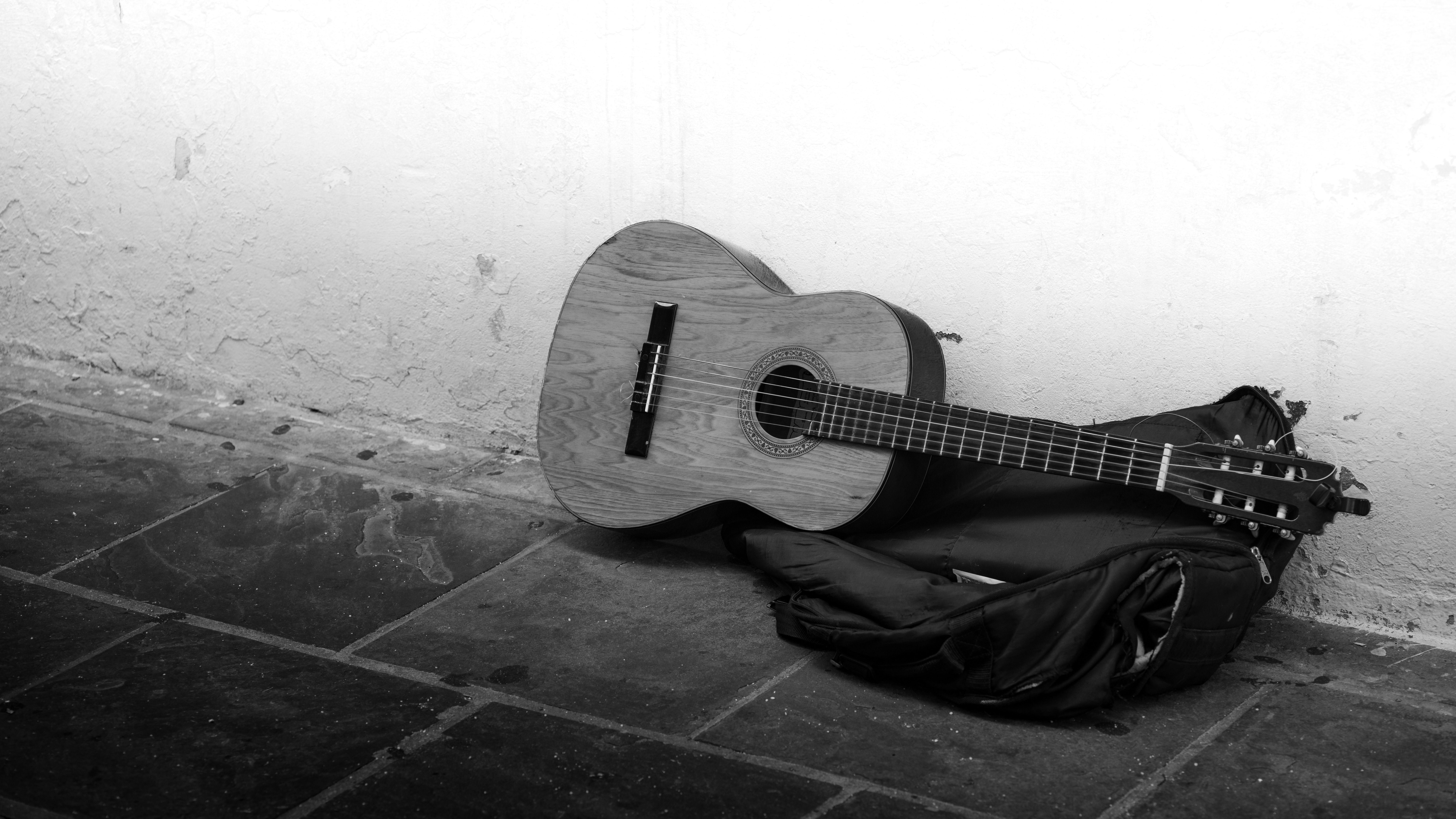 Black-and-white photo of an acoustic guitar leaning against a wall, evoking Americana songwriting