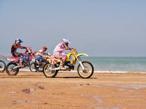 Motocross bikers tackle the sandy beach of Margate, UK, under a sunny sky.