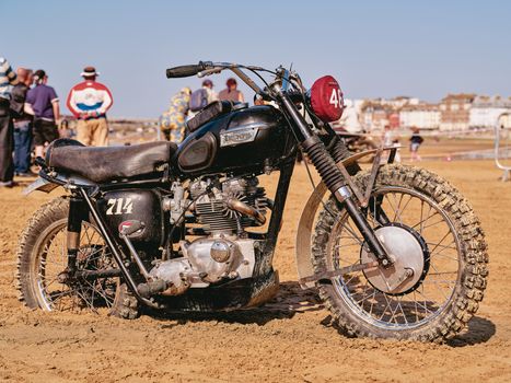 Classic Triumph motorcycle on Margate beach during a vintage rally on a sunny day.