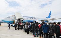 Travelers at an airport embarking a XiamenAir plane on a clear day.