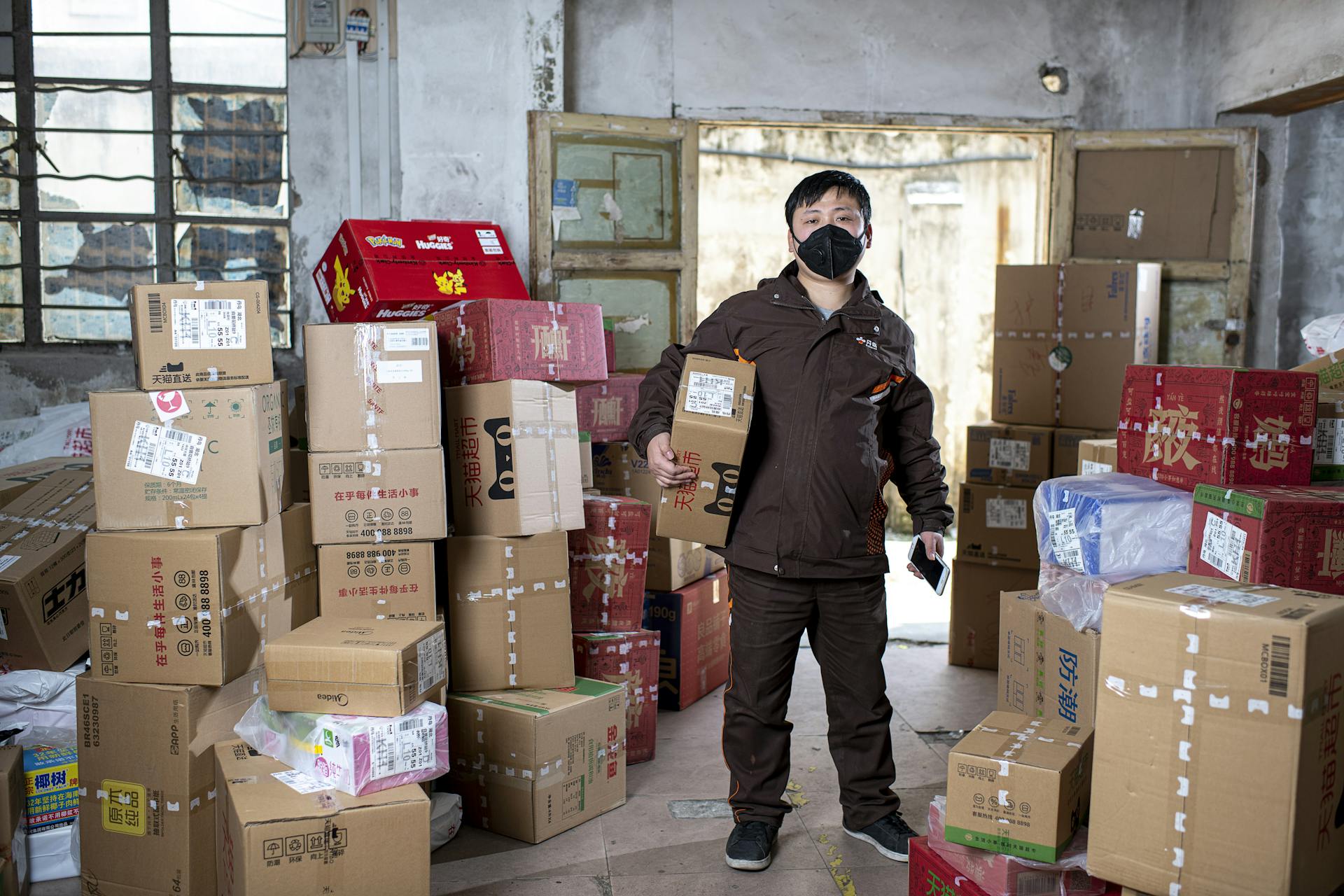 Employee with a Package and a Smartphone in the Warehouse