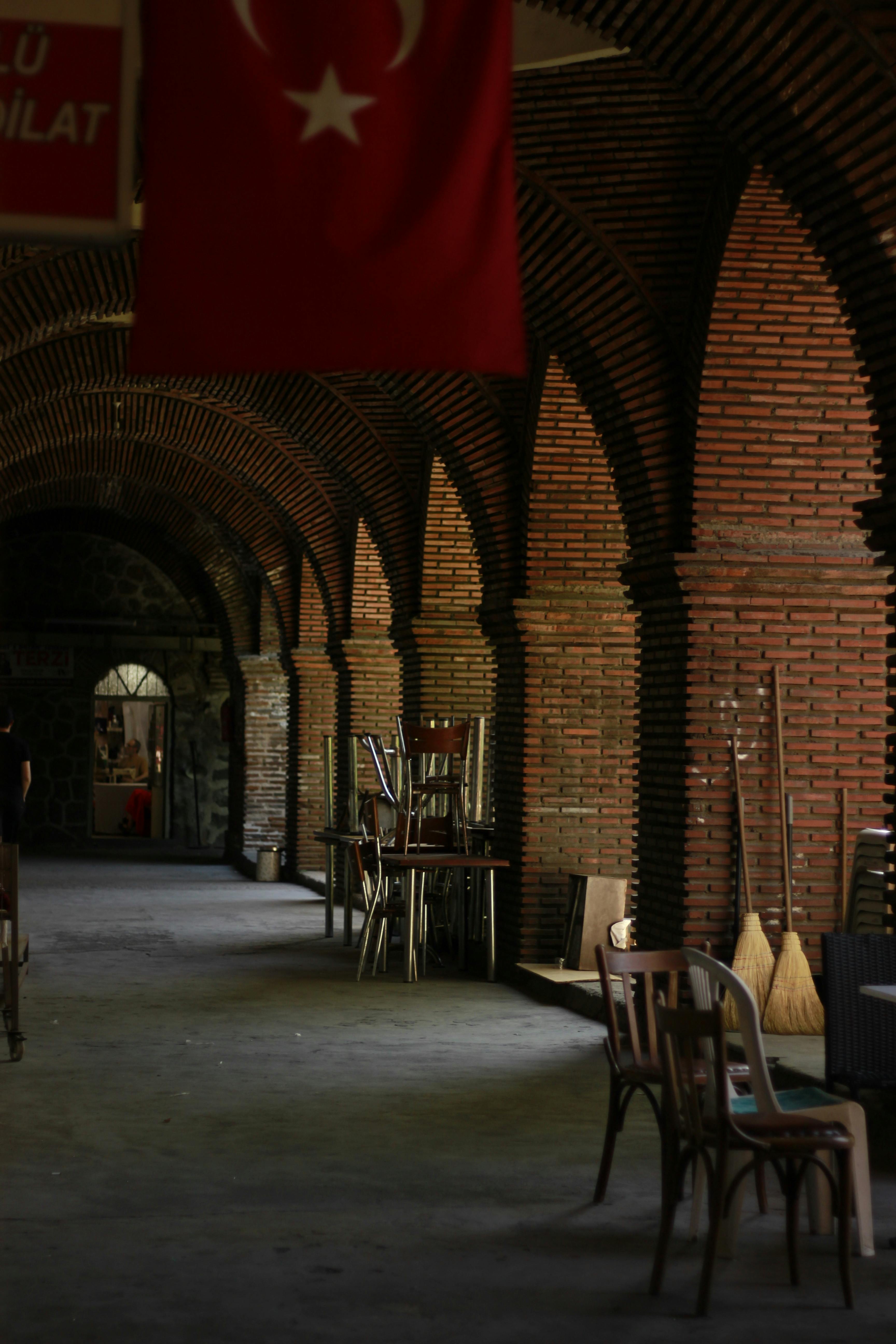 Atmospheric indoor corridor with brick arches and a Turkish flag hanging prominently.