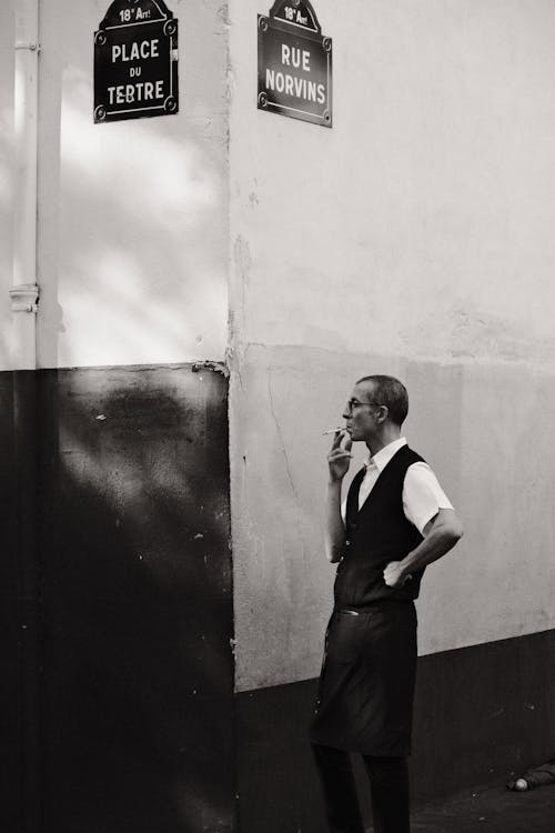 A man in a vest and tie smoking a cigarette