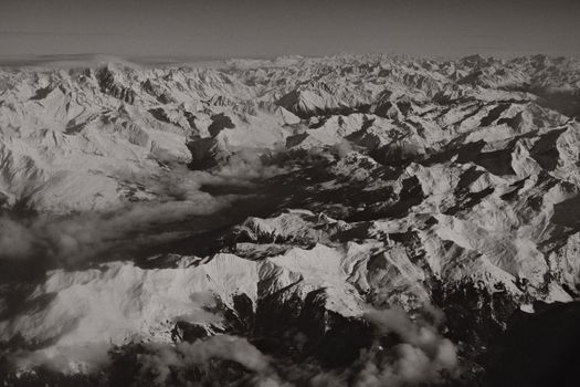 Breathtaking aerial view of snow-covered mountain ranges in black and white.