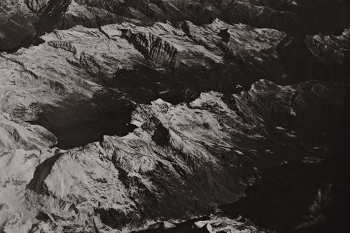 Free Black and white aerial photograph of a snowcapped mountain range with rugged, rocky terrain. Stock Photo