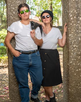 Fashionable couple wearing sunglasses and white t-shirts pose confidently in a park in Ciudad de México.