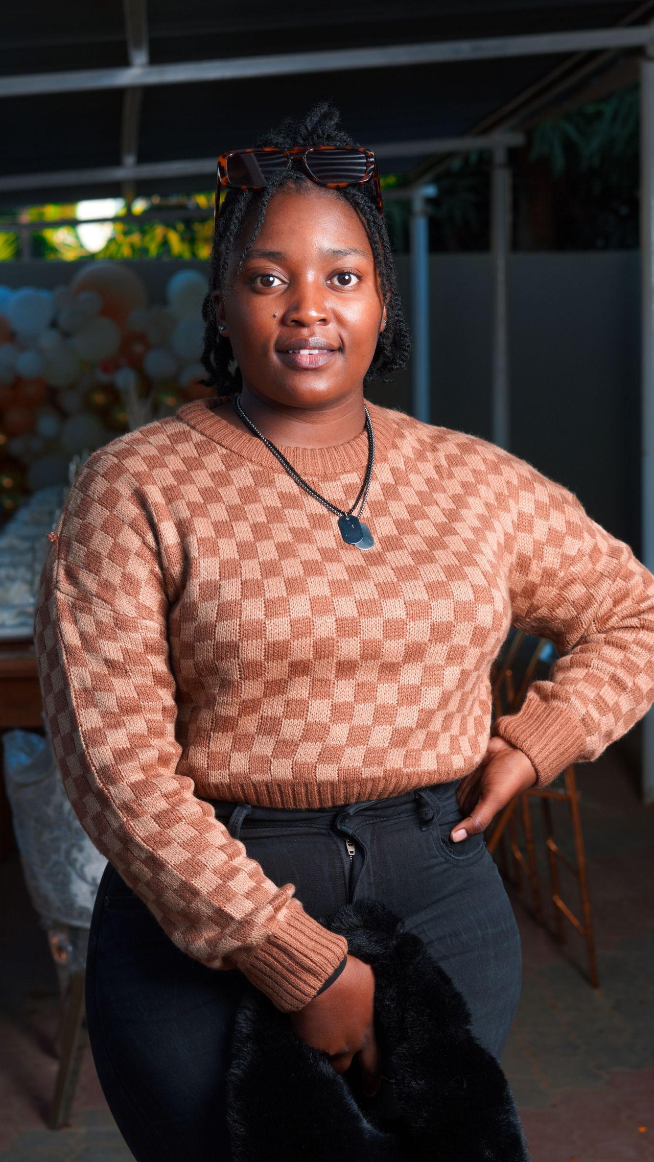 Woman in a caramel and cream checkerboard knit sweater with black jeans