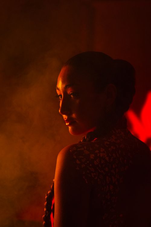 Free A contemplative woman in a dramatic red-lit portrait with smoky shadows. Stock Photo
