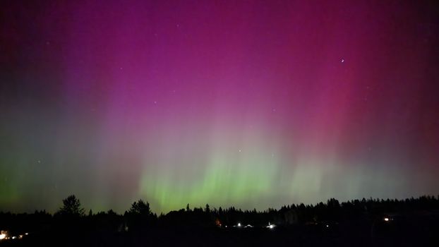 Stunning aurora borealis display with pink and green hues over a rural Oregon landscape at night.
