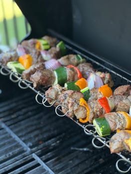 Delicious grilled meat and vegetable skewers cooking on a barbecue grill.