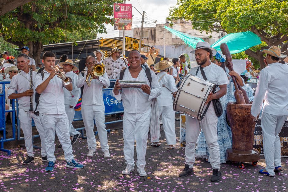 A lively group of musicians plays instruments at an outdoor street festival, bringing vibrant music to the crowd.