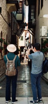 Two men explore a narrow, historic alley in Antalya, capturing the architecture.