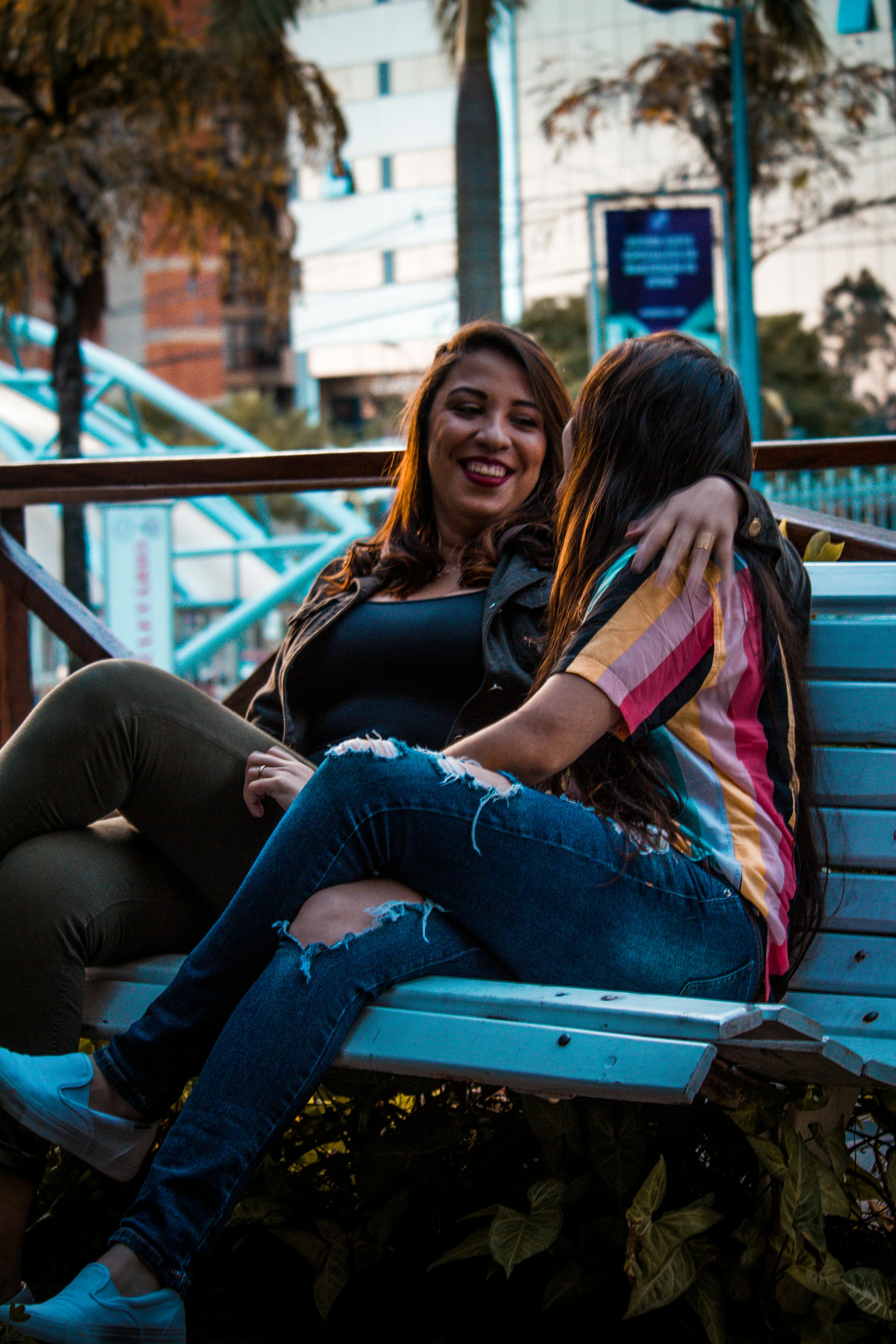 two women sitting on white wooden bench