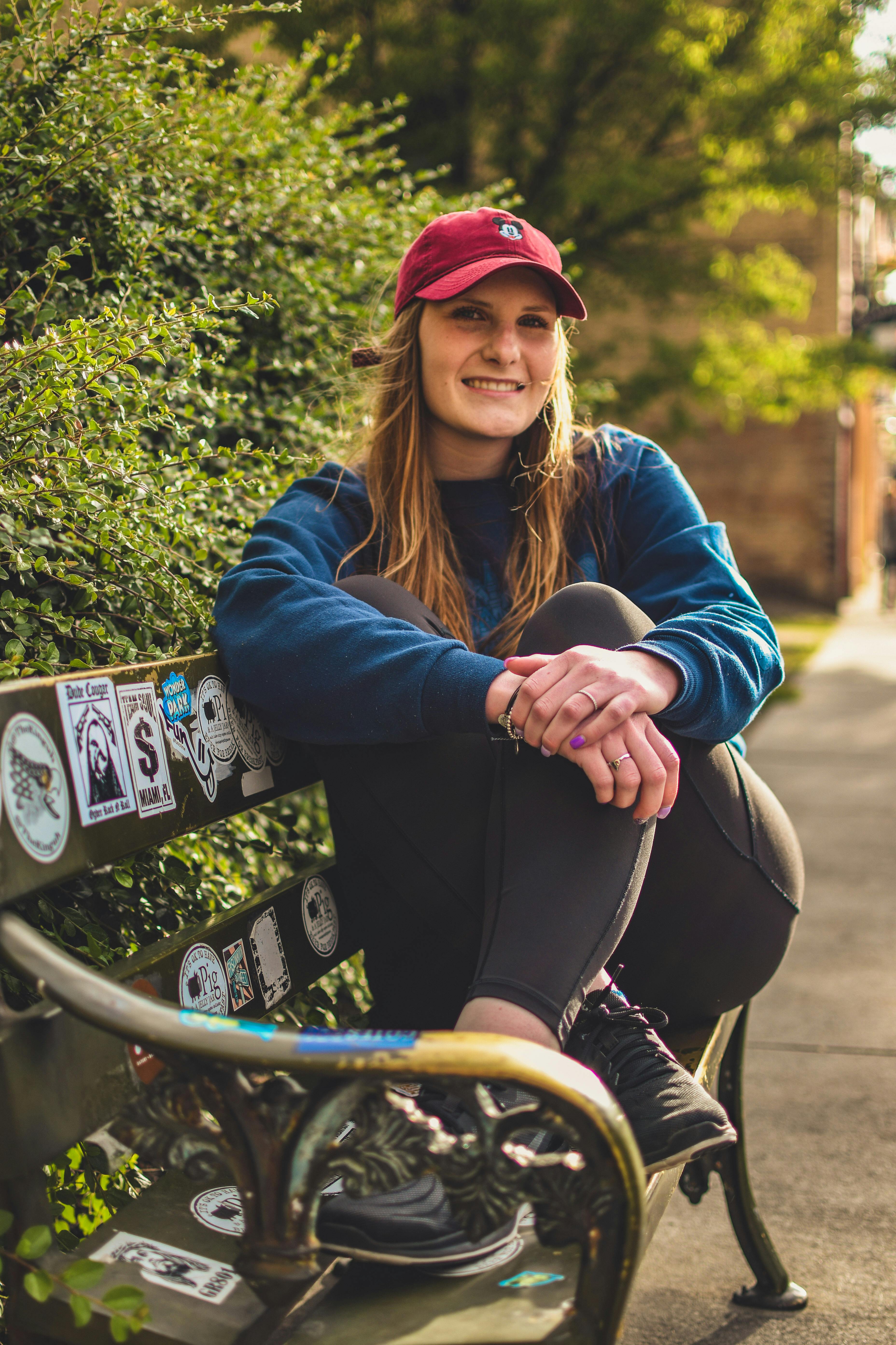 一位穿着休闲装的年轻女子，正坐在公园的长凳上微笑