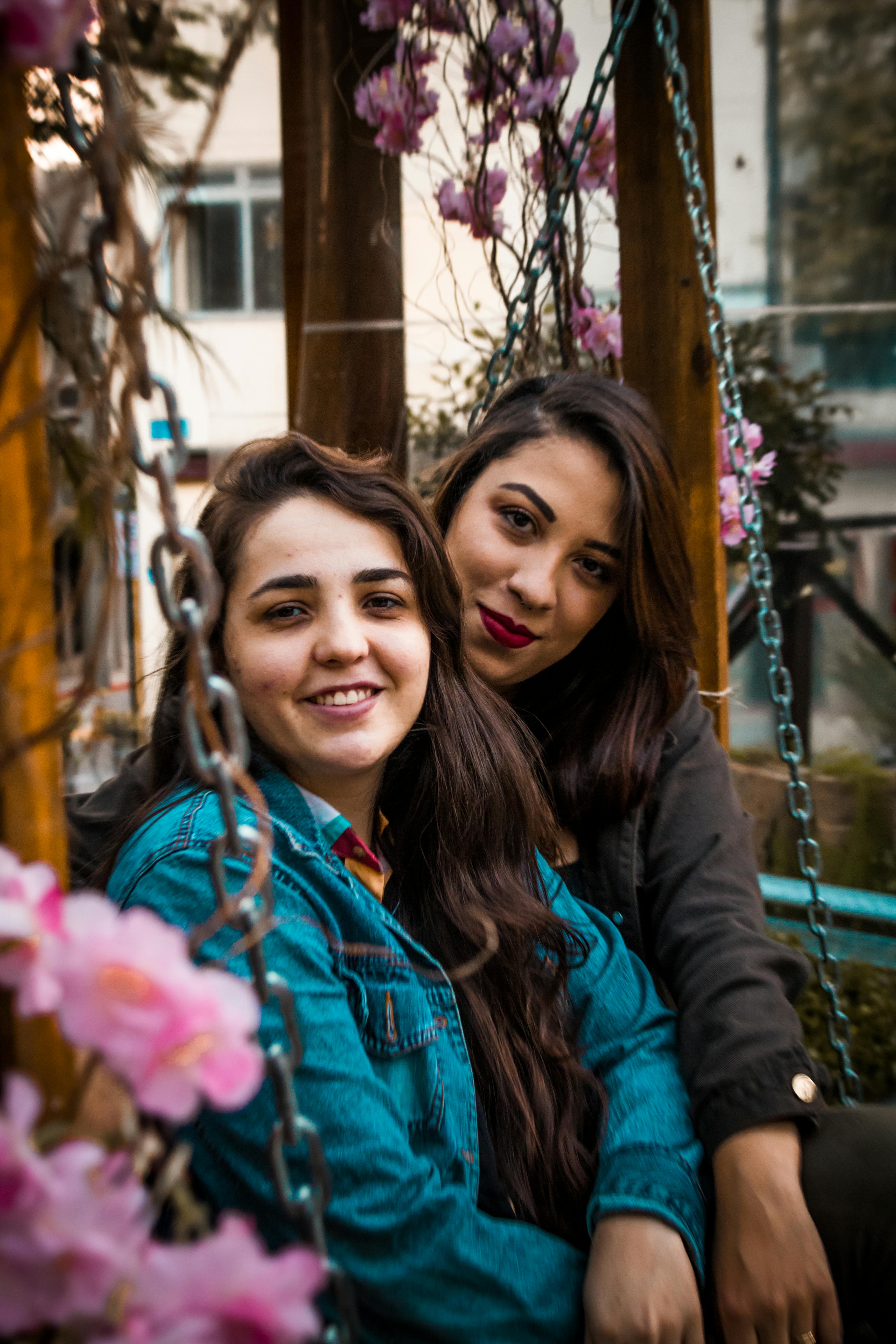 two women sitting on swing bench