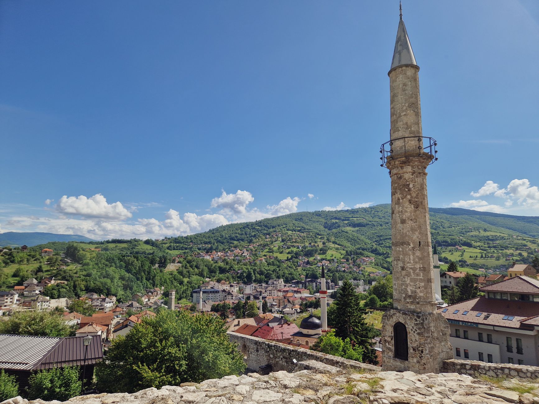 A beautiful scenic view of a Bosnian town featuring a prominent mosque minaret against a clear blue sky.