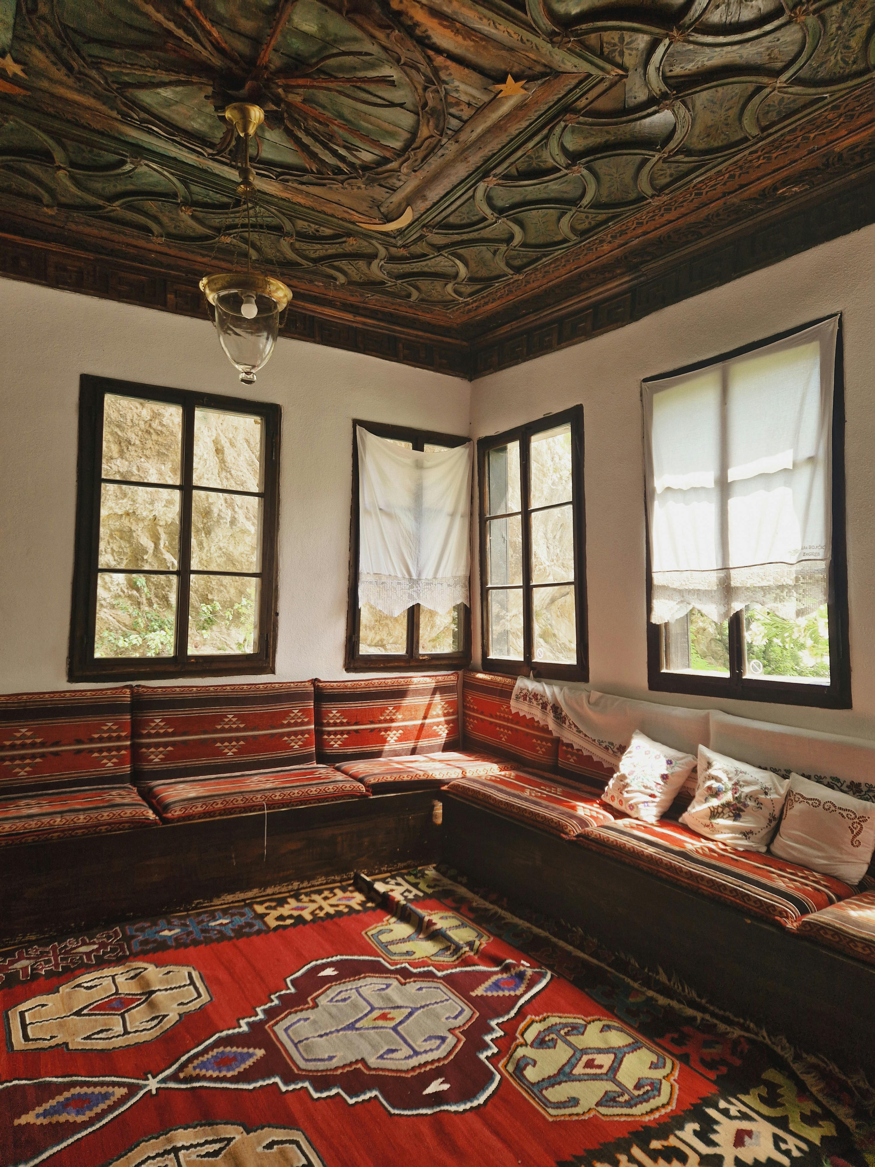 Explore a cozy Bosnian room with ethnic carpets and seating, capturing cultural elegance.