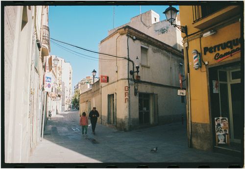 Free Father and child walking through a sunny urban street, vibrant buildings around. Stock Photo