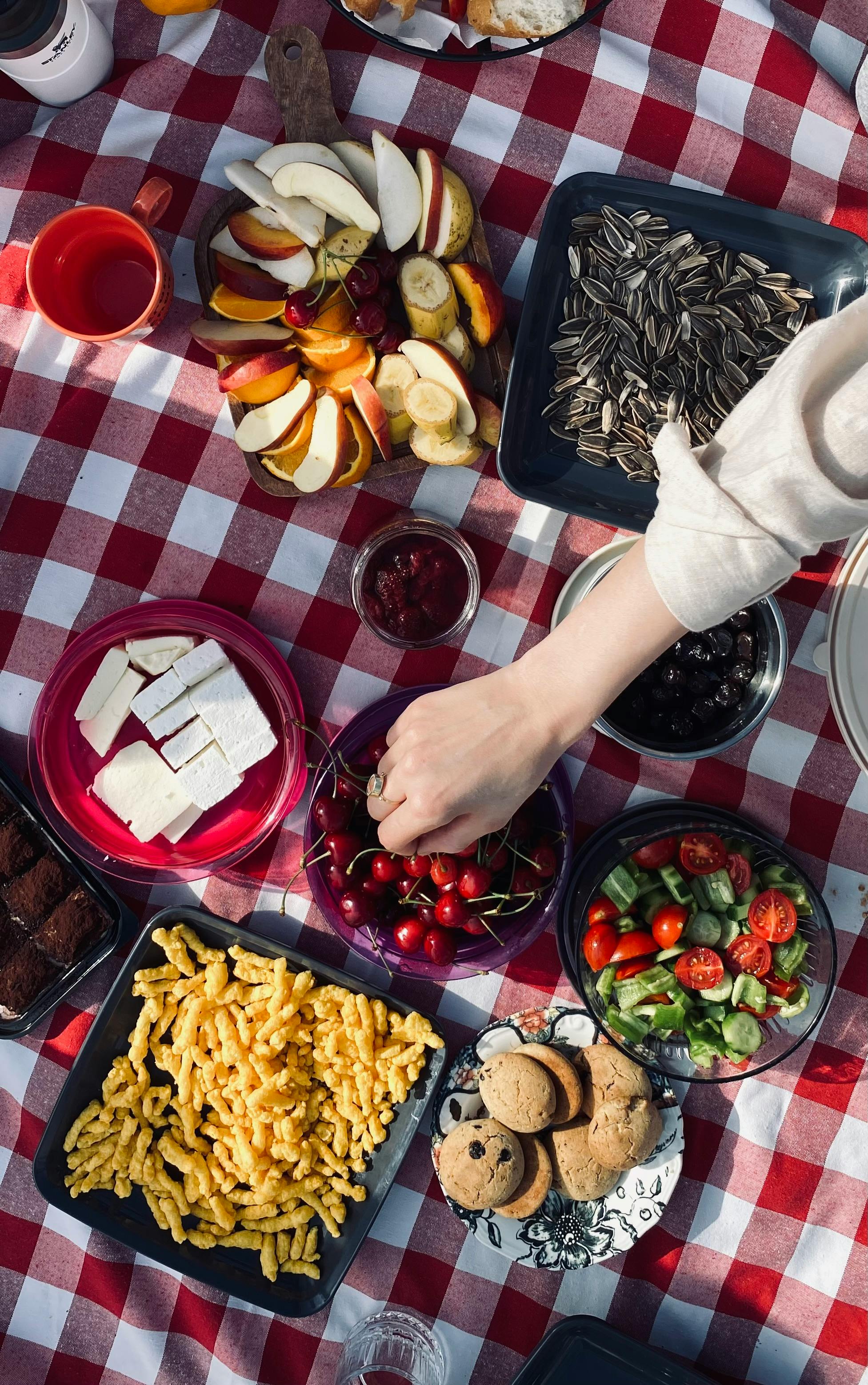 Enjoy a vibrant summer picnic with a variety of snacks and fruits on a checkered blanket.