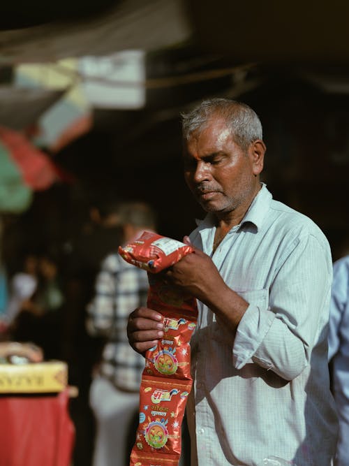 A man holding a bag of snacks in a market