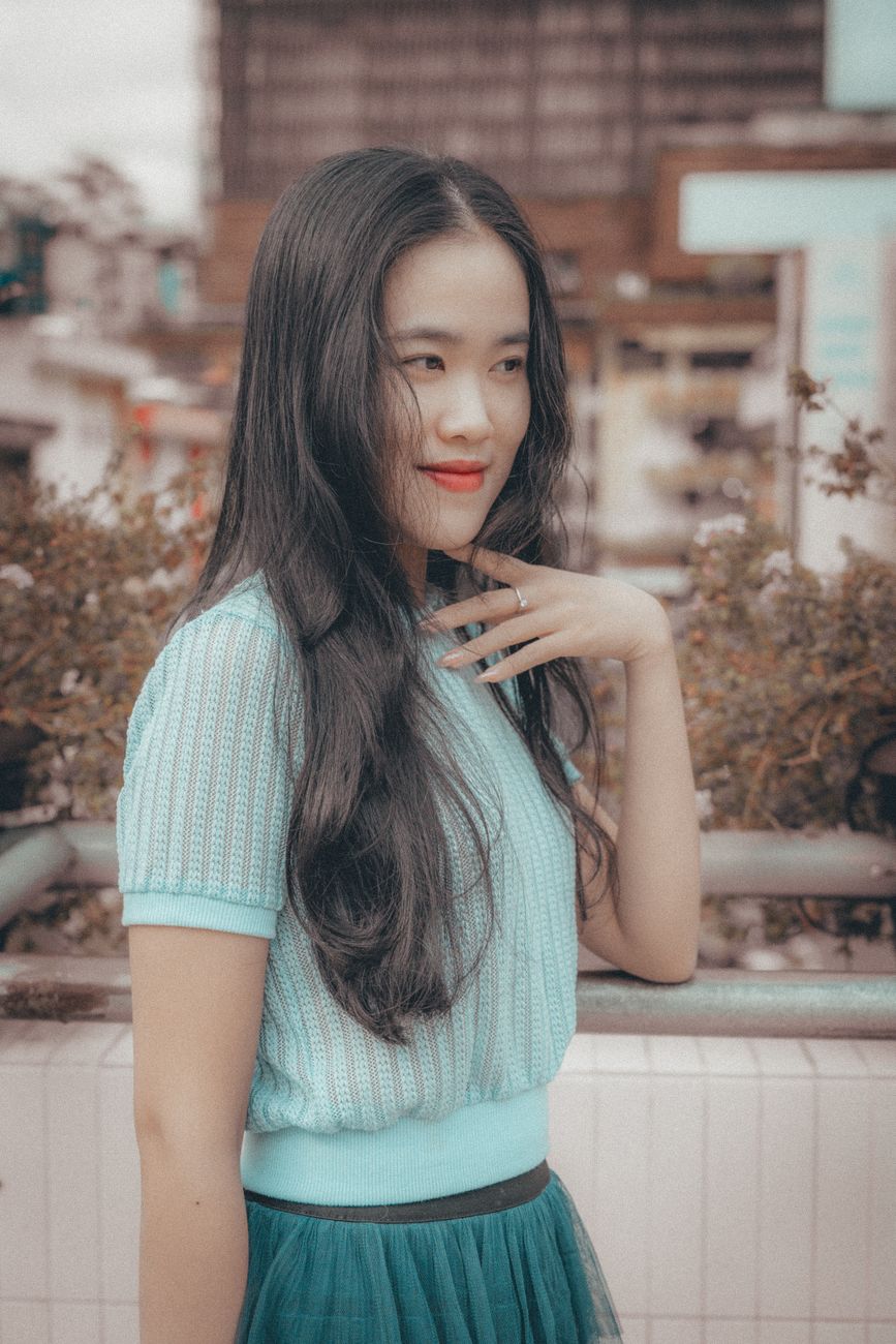 Portrait of a young woman in Dalat, Vietnam, smiling in an urban setting with stylish blue outfit.