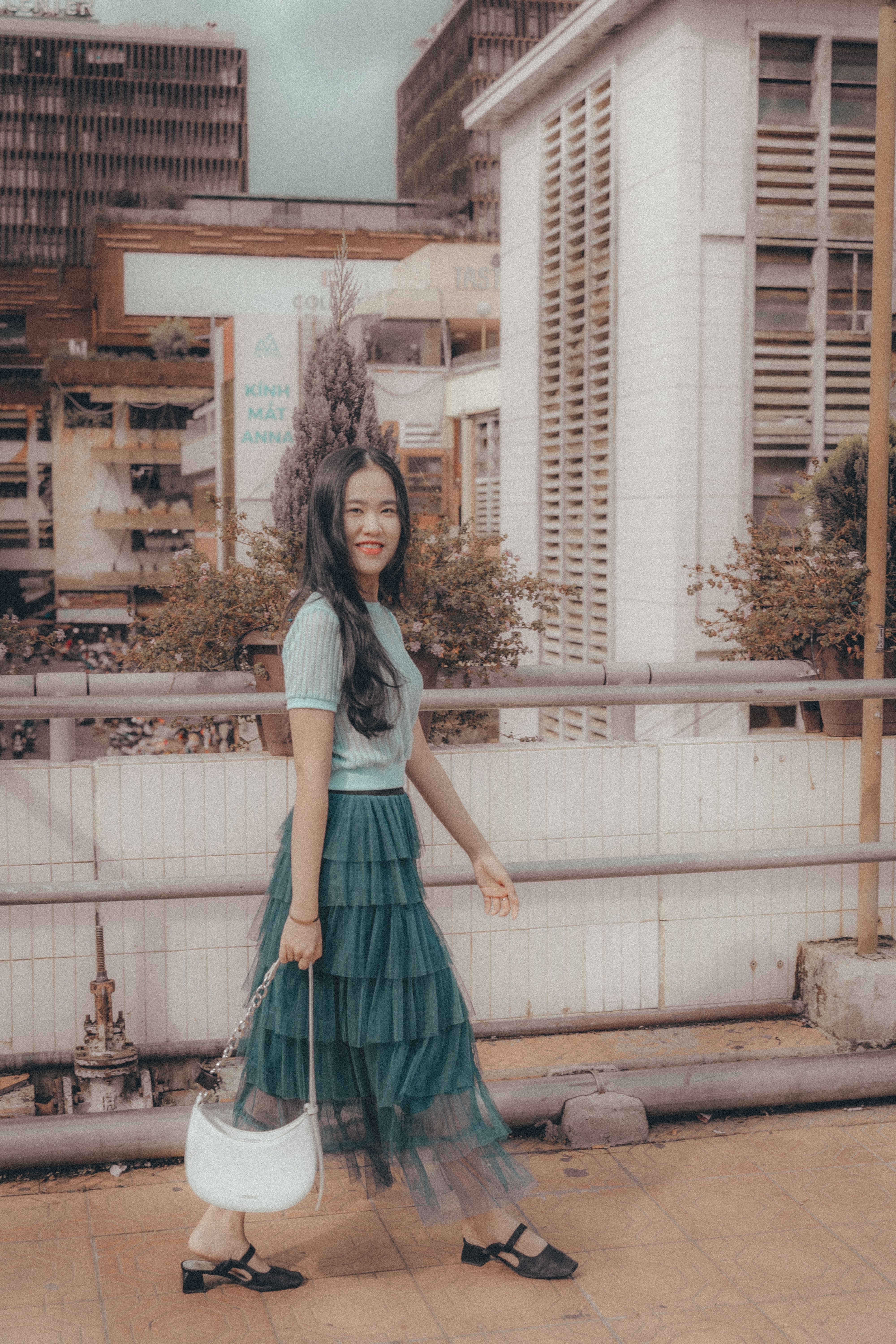 Woman in fashionable attire walking by urban buildings in Dalat, Vietnam.