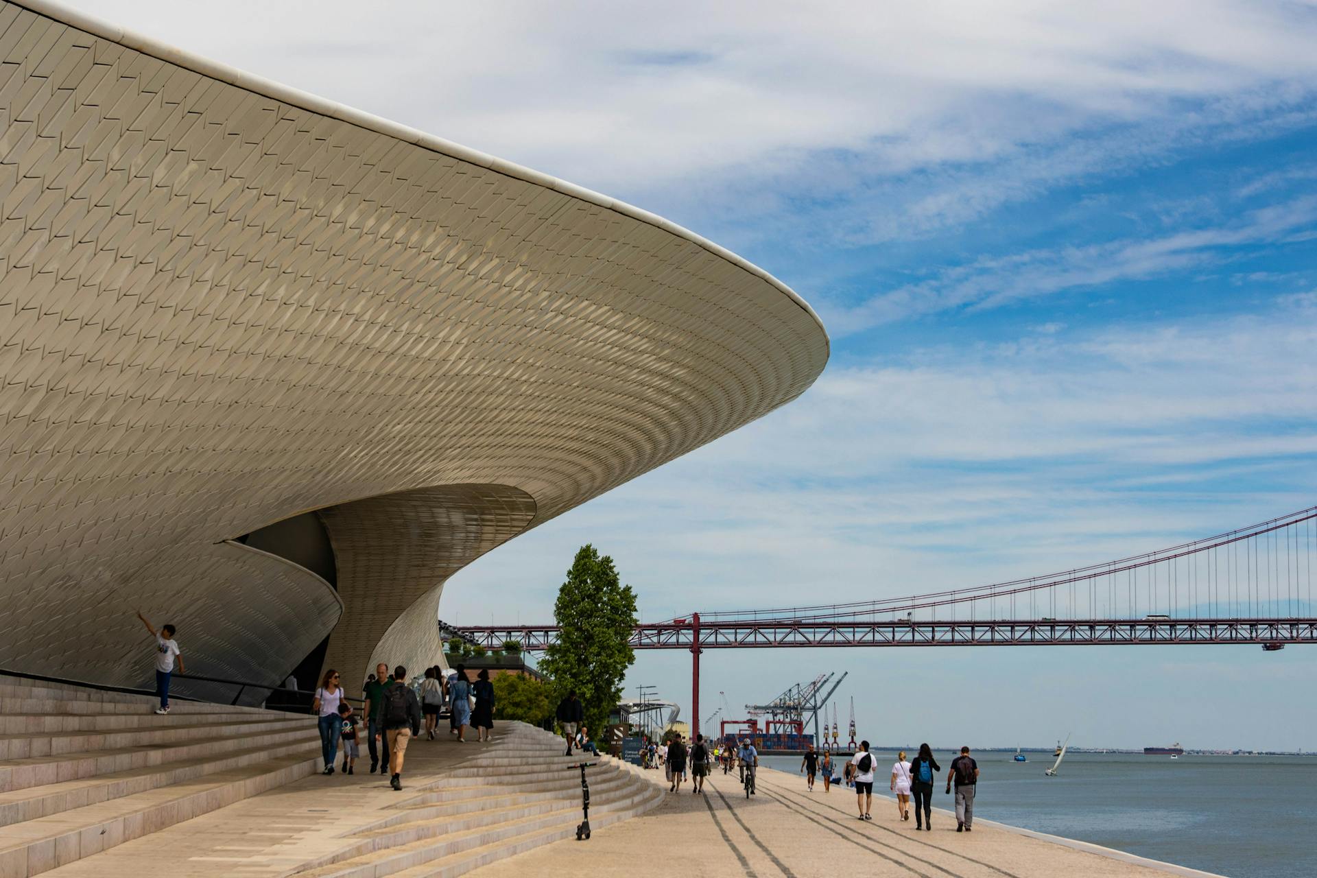 Explore the modern architecture and scenic walkway in Lisbon with a clear blue sky backdrop.