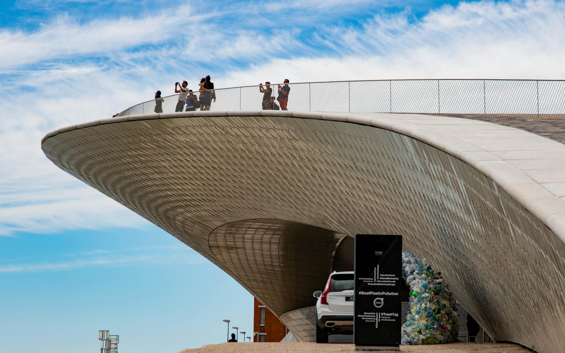 Contemporary architectural structure in Lisbon with visiting tourists under a clear sky.
