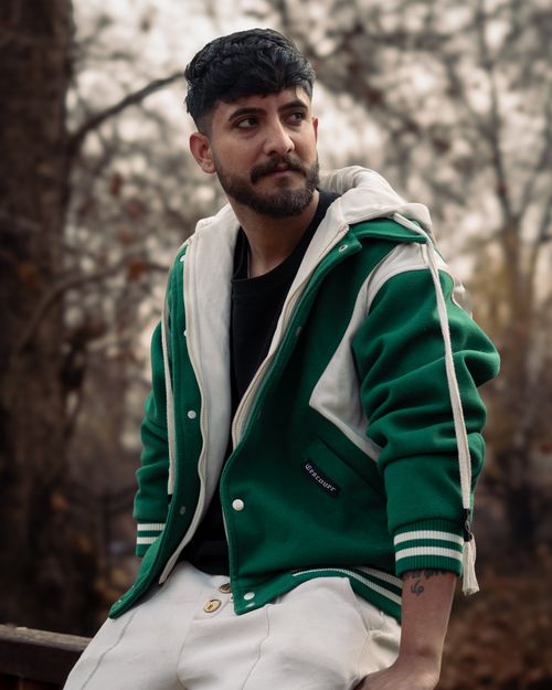Free Portrait of a man in a green jacket sitting outdoors, exuding a calm and contemplative mood. Stock Photo