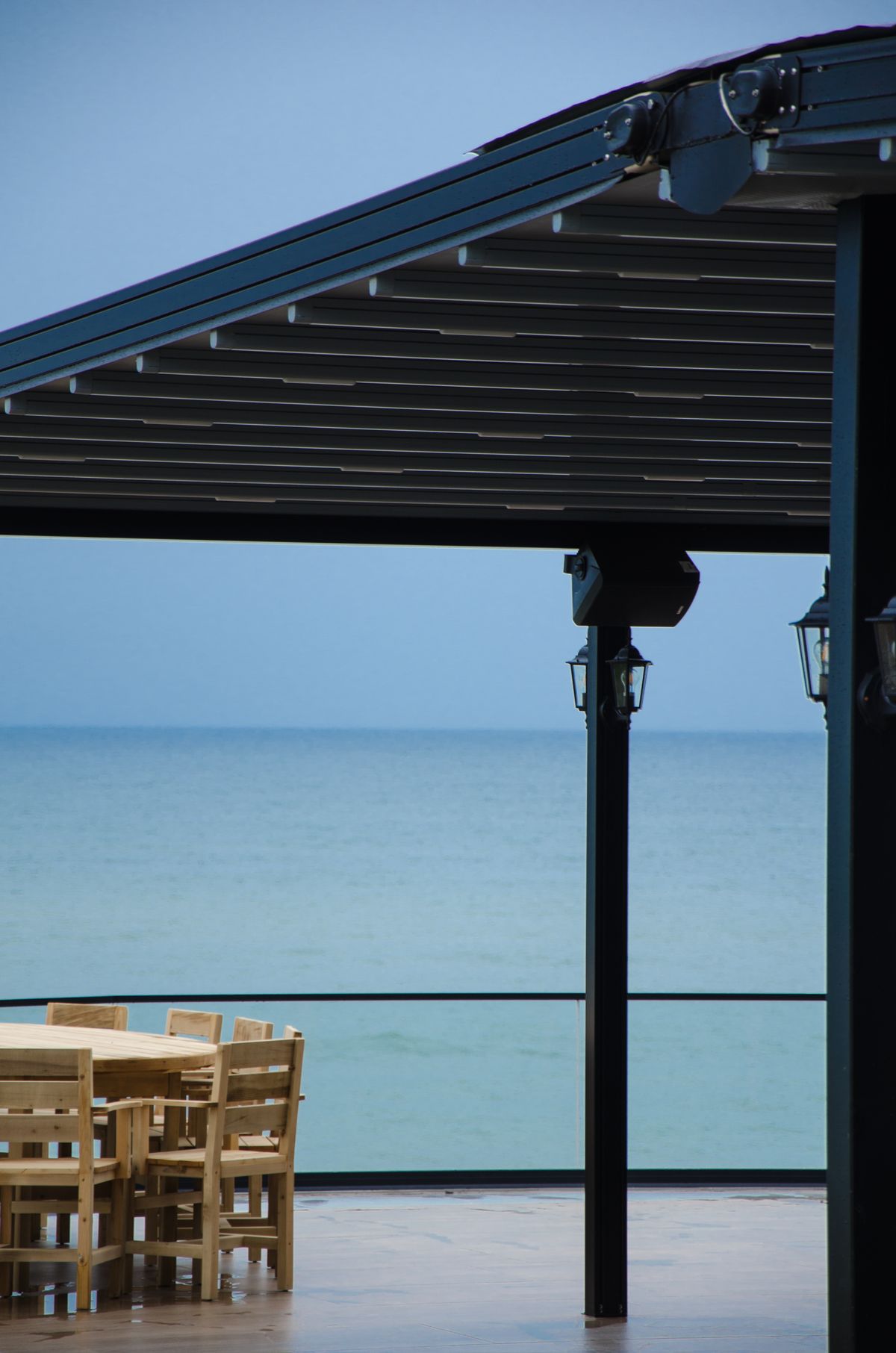 Nahaufnahme der Lamellen-Mechanik an einem Aluminium-Lamellendach mit Blick aufs Meer