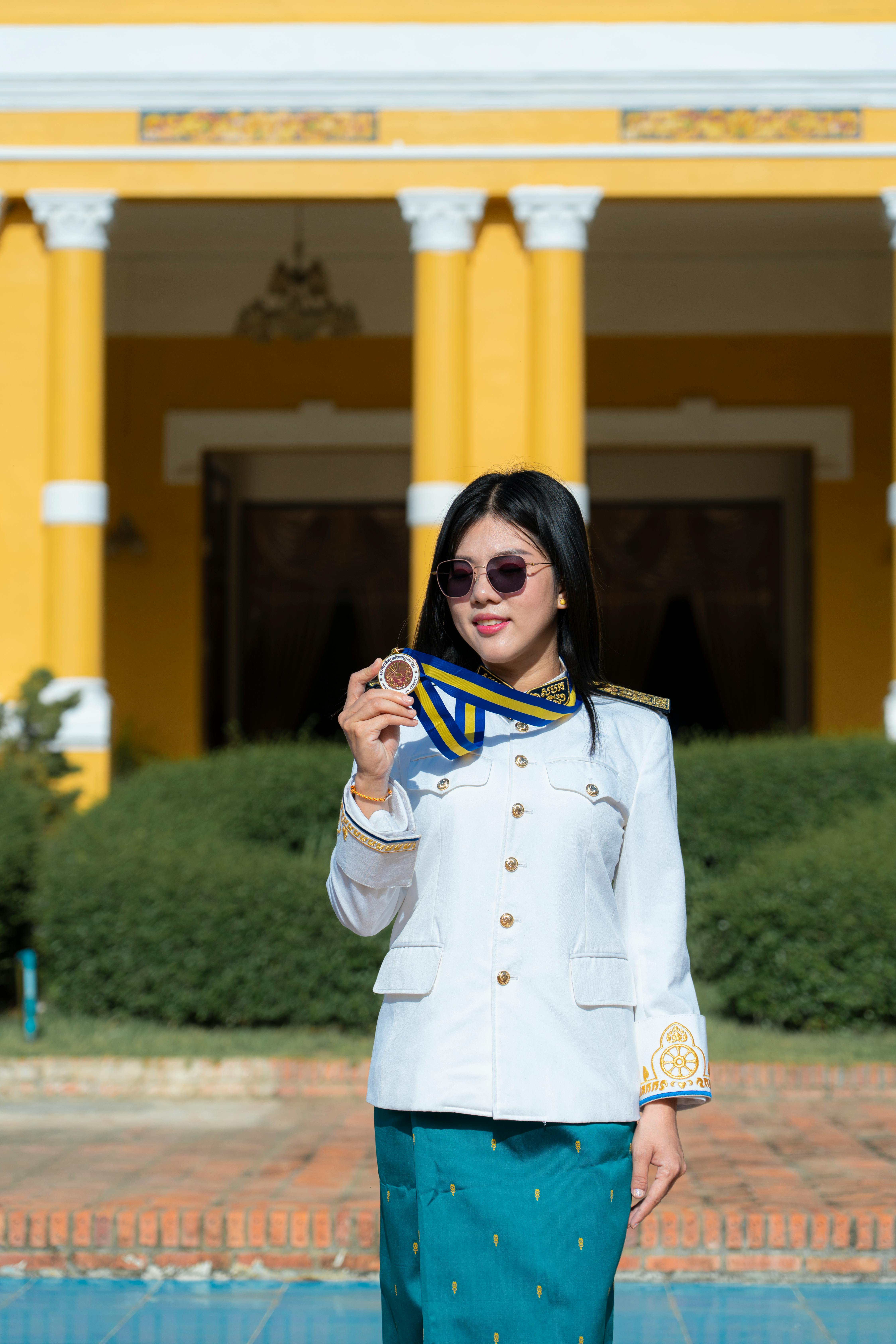 a woman in a white uniform and sunglasses is standing in front of a yellow building