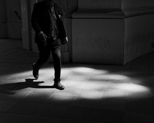 A man walking in the shadows of a building