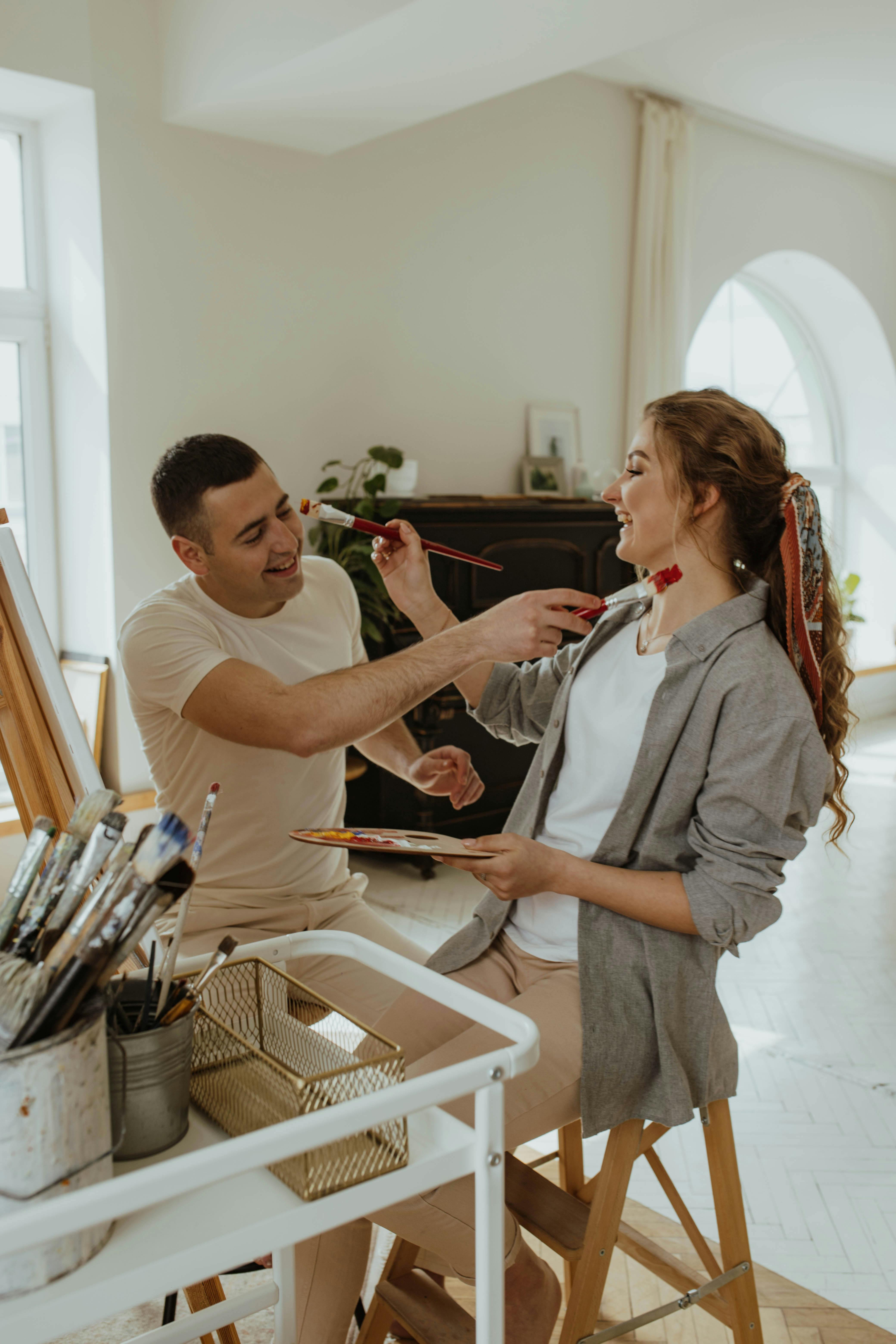A couple enjoying a playful painting session in a bright, modern studio.
