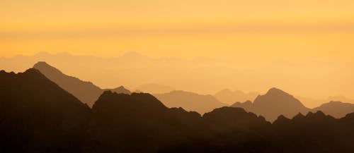 A sunset over mountains with a silhouette of a person