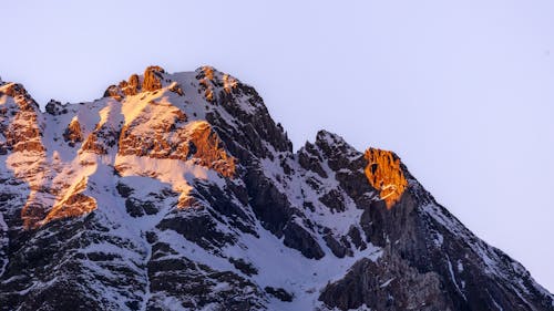 A mountain peak with snow on it at sunset
