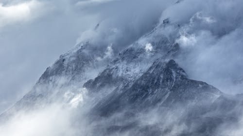 A mountain range covered in clouds with snow on top