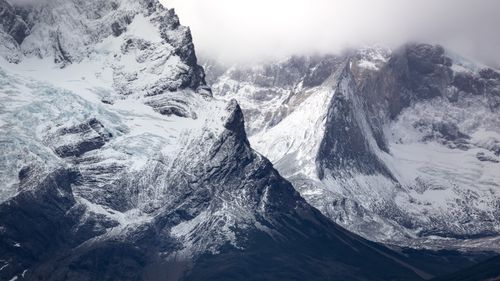 Free Majestic snow-capped mountains with dramatic rock formations and foggy atmosphere. Stock Photo