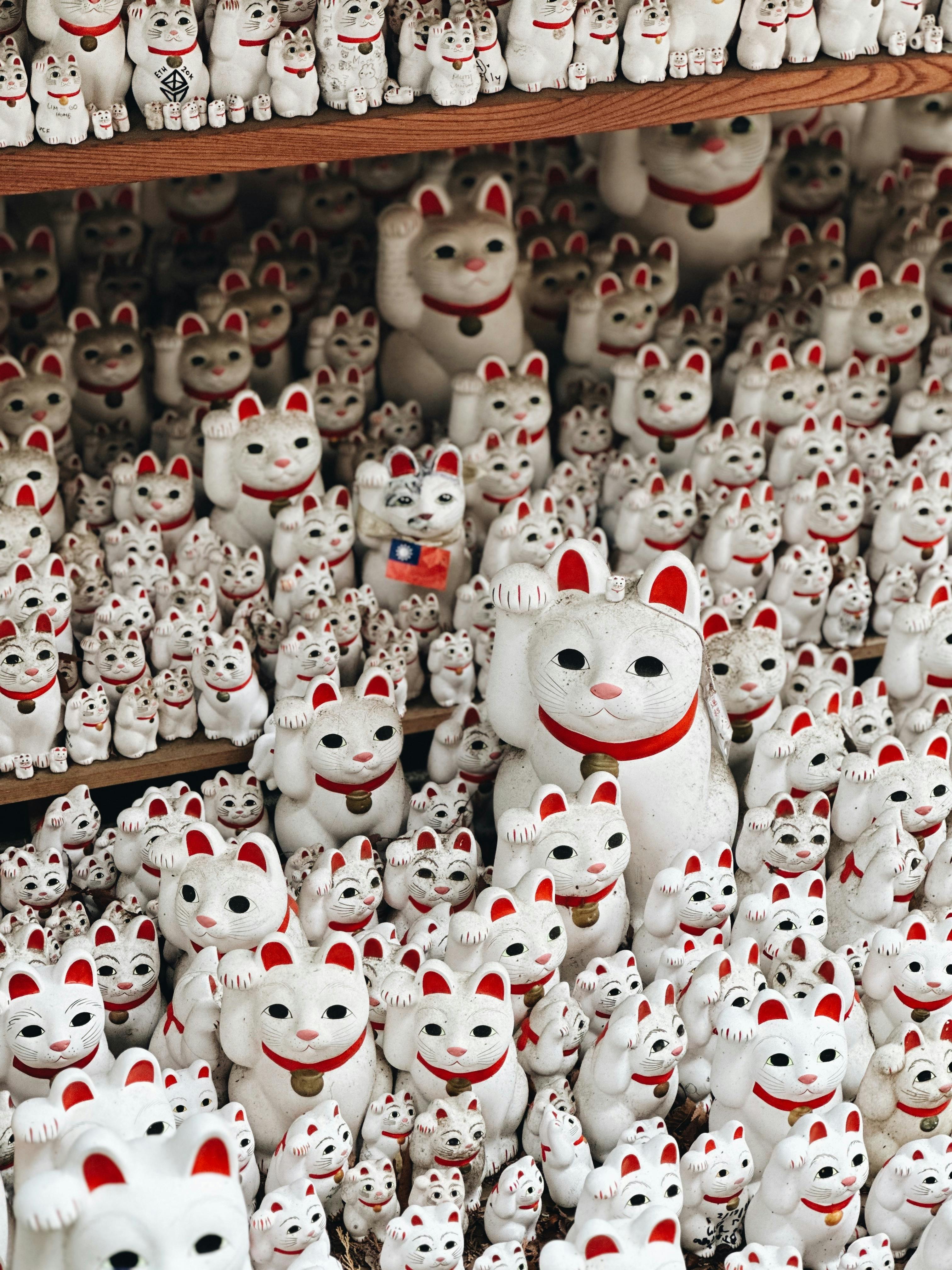 Hundreds of Maneki-neko figurines in a close-up view, symbolizing luck and prosperity.